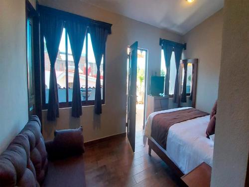 a bedroom with a bed and a window with blue drapes at Hotel Suites La Fortuna in Mazamitla