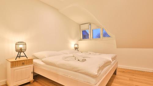 a white bedroom with a bed and a window at Traumgarten Haus Traumoase in Prerow
