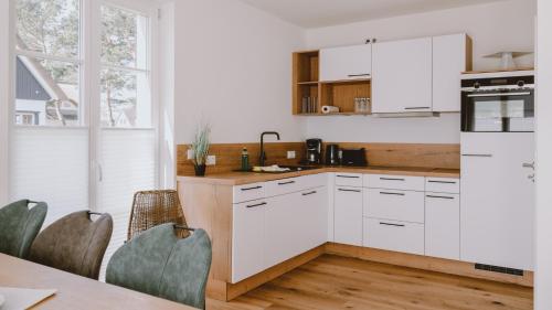 a kitchen with white cabinets and a table with chairs at Traumgarten Haus Leichte Brise in Prerow