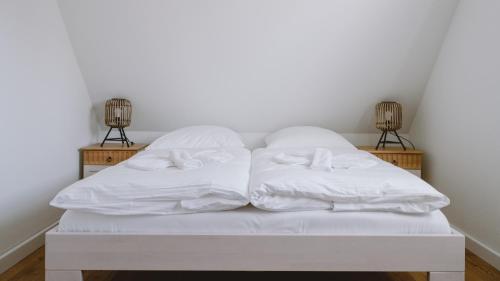 Una cama blanca con dos almohadas. en Traumgarten Haus Leichte Brise en Prerow