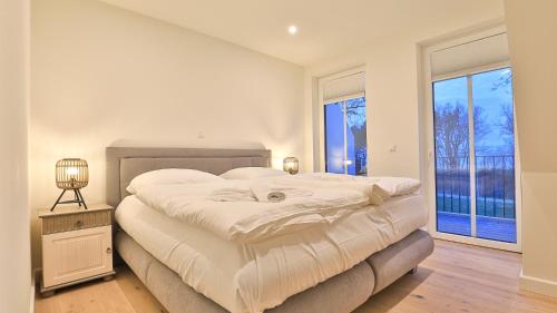a white bedroom with a large bed and windows at Strandhaus Zingst Apartment 14 in Zingst