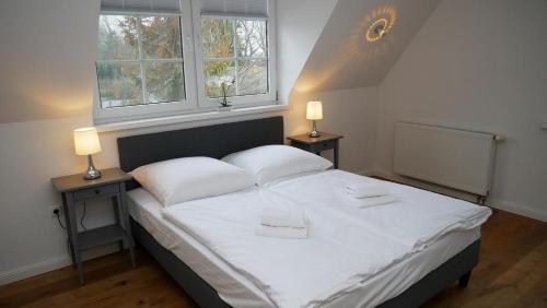 una camera da letto con un grande letto bianco con due lampade di Windflüchter Treibholz a Prerow