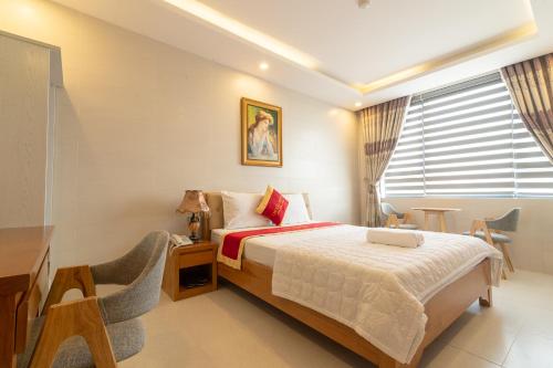a bedroom with a bed and a desk and a window at Lam Kiều Hotel in Vung Tau