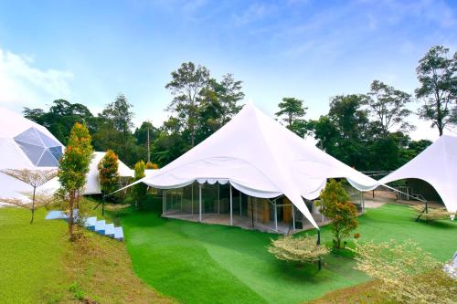 a house with two white tents on a green lawn at Glamz at Genting in Genting Highlands