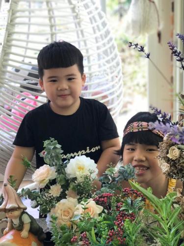 two young boys sitting at a table with flowers at 花蓮 達芙妮花園民宿 in Jian