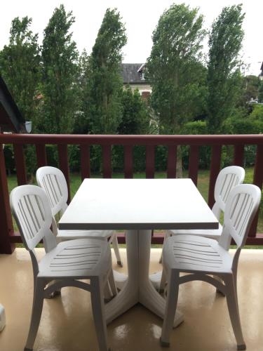 une table blanche et quatre chaises sur une terrasse couverte dans l'établissement Cabourg, T2 parfait pour vous ! Proche plage et centre-ville, 2 à 4 pers., à Cabourg