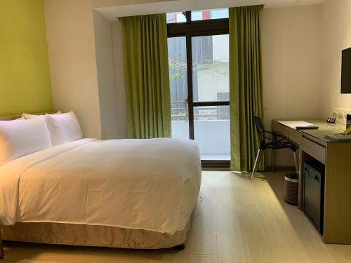 a bedroom with a bed and a desk and a window at CHECK inn SELECT Hualien LinSen in Hualien City