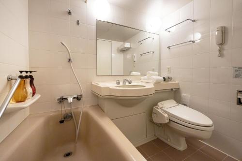 a bathroom with a toilet and a sink and a tub at Chigusa Hotel in Kitakyushu
