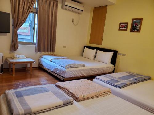 a room with three beds in it with a window at Youran B&B in Jiufen
