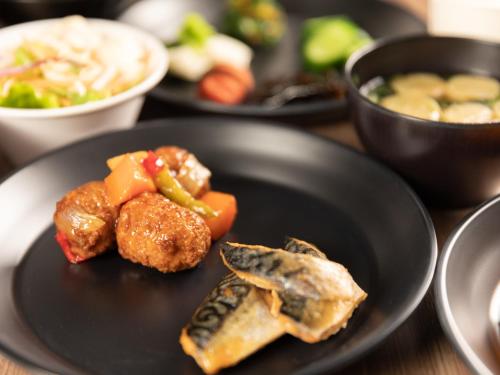 a black plate with food on a wooden table at Super Hotel Ishikawa Nomineagari Smart Inter in Nomi