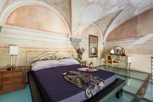 Villa Guinigi Dimora di Epoca Exclusive Residence & Pool في لوكّا: غرفة نوم بسرير في غرفة بسقوف