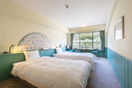 a hotel room with two beds and a table at Tabist Kinugawa Park Cottage in Nikko