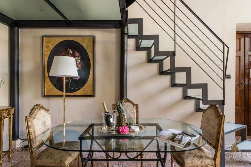 a dining room with a glass table and a staircase at Villa Guinigi Dimora di Epoca Exclusive Residence & Pool in Lucca