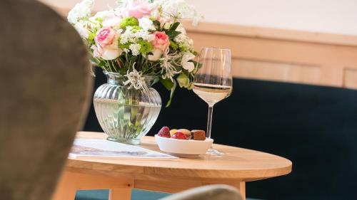 a table with a vase of flowers and a glass of wine at Das Homann in Samnaun