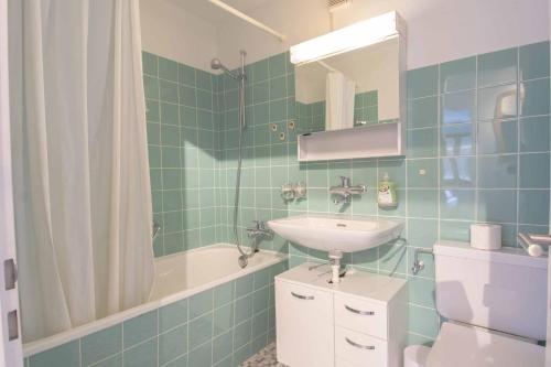 uma casa de banho com azulejos verdes, um lavatório e uma banheira em Ferienwohnung Titschermatte em Adelboden