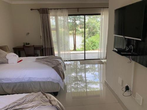 a bedroom with two beds and a large window at Juda Haus Lodge in Katima Mulilo