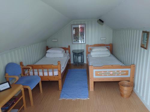 a room with two beds and a chair and a table at Vandrarhemmet Tallbacka/Ängelsberg Hostel in Ängelsberg
