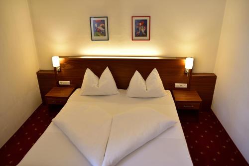 a bedroom with a large white bed with two pillows at Hotel Krone in Brunico