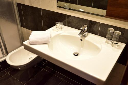 a bathroom with a white sink and a toilet at Hotel Krone in Brunico