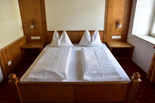 a bed with white sheets and pillows on it at Hotel Krone in Brunico
