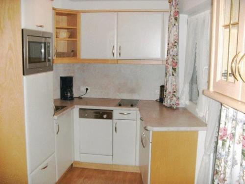 a small kitchen with white cabinets and a microwave at Pension Steiner in Mayrhofen