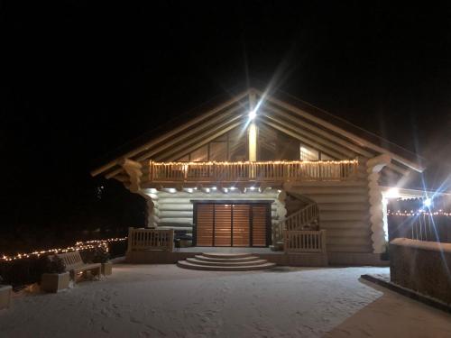 a log cabin with lights on it at night at Adele in Mizhhirʼʼya