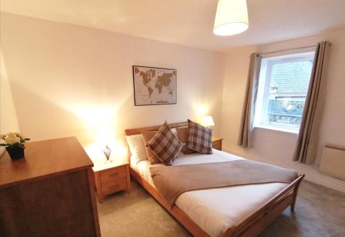 a bedroom with a bed with a desk and a window at Seaside Apartment in Oban