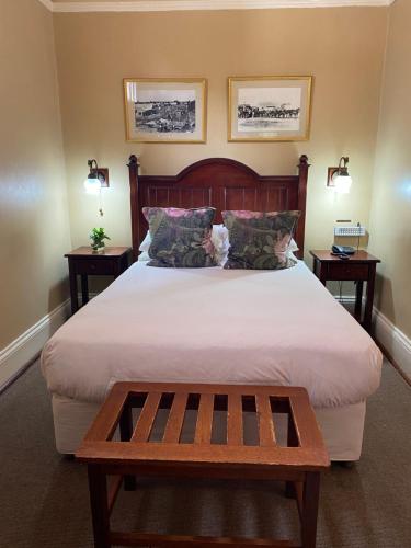 a bedroom with a large bed with a wooden headboard at Kimberley Club Guesthouse in Kimberley