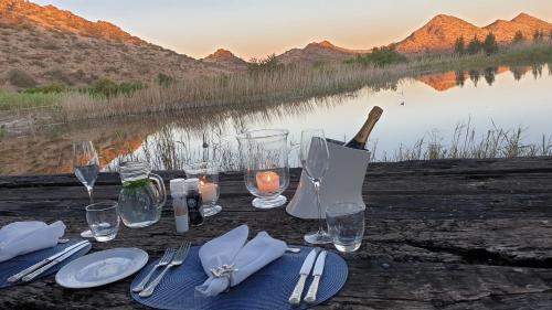 a table with plates and glasses and a bottle of wine at Big Sky Ranch in Colesberg