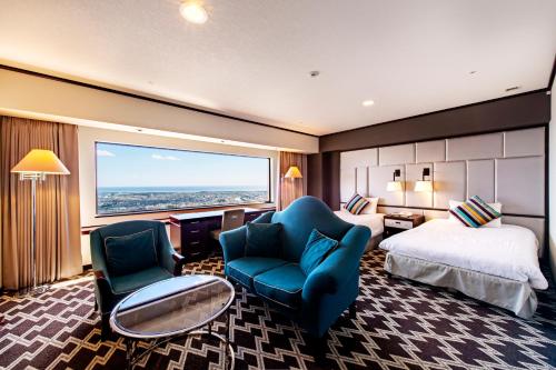 浜松市にあるオークラアクトシティホテル浜松のベッド、ソファ、椅子が備わるホテルルームです。