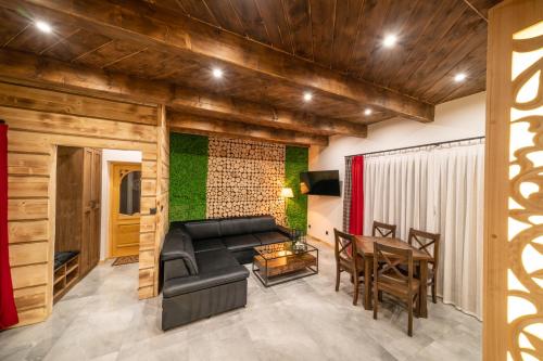a living room with a black couch and a table at Luxury Houses & Apartments Zaliński in Zakopane