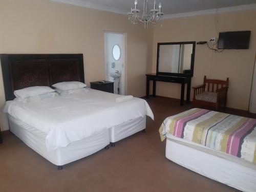 a bedroom with two beds and a table and a mirror at Hazelonz Bed &Breakfast in Pretoria