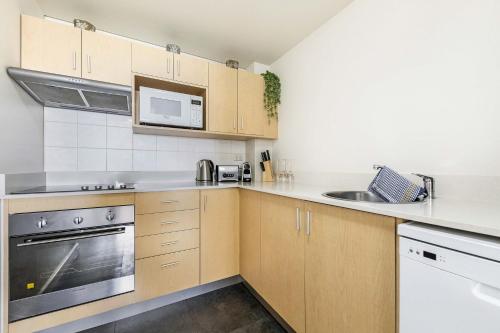 a kitchen with wooden cabinets and a sink at ZEN AT THE ESPLANADE - Spectacular Sunset Retreat in Darwin