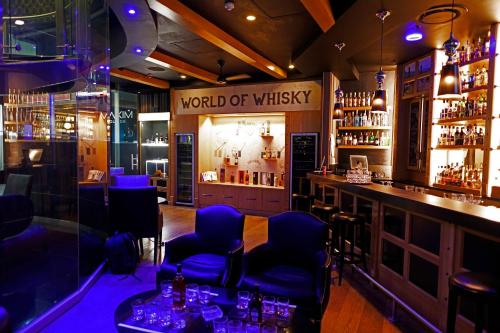 a bar with blue chairs and a sign that reads world of whiskies at DAVINCI Suites in Johannesburg