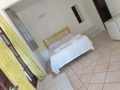 a bedroom with a bed with white sheets at Pousada Canoa Beach in Canoa Quebrada