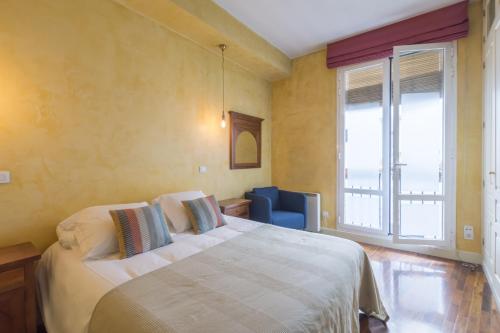 1 dormitorio con 1 cama grande y 1 silla azul en MIT House San Miguel en Madrid, en Madrid