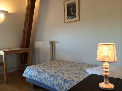 um quarto com uma cama e um candeeiro sobre uma mesa em Couvent de Saint-Ulrich em Sarrebourg
