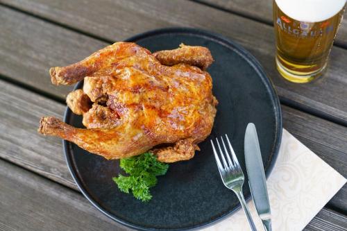 a black plate with a piece of chicken and a glass of beer at Landhotel Gockelwirt in Eisenberg