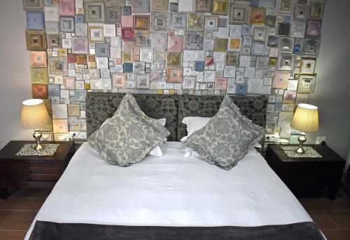 a bedroom with a large bed with two lamps and pictures on the wall at Rabbit Hole Hotel in Krugersdorp