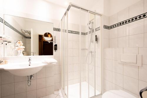 a white bathroom with a shower and a sink at Ringhotel Klövensteen in Stadt Schenefeld