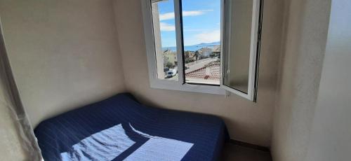 un lit dans une chambre avec une fenêtre dans l'établissement LE MIRAMAR Appartement face à la mer - Balcon - Clim, à Saint Cyprien Plage