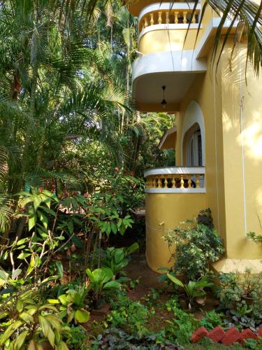 a building with a balcony in the middle of a garden at Palm Grove Cottages - Leisure Resort in Benaulim