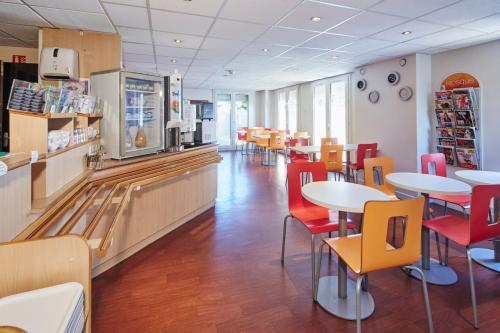 a restaurant with tables and chairs and a bowling alley at Premiere Classe Cergy Saint Christophe in Cergy