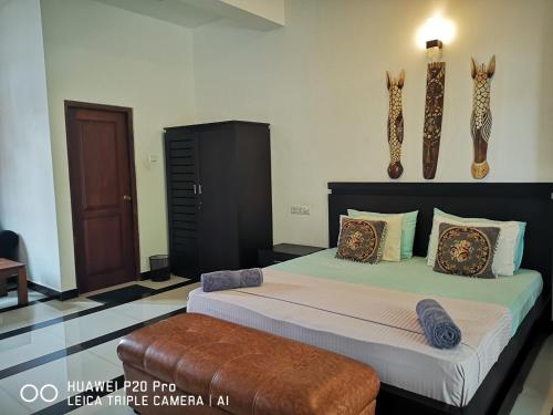 a bedroom with two beds and a brown ottoman at Serendib Village Guest House in Negombo