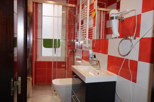 y baño con lavabo, aseo y azulejos rojos. en Hostel GoodHouse Gijón, en Gijón