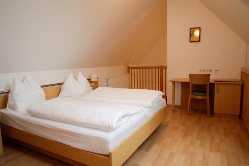 a bedroom with a white bed and a table at Raiffeisenhof Appartements in Ehrenhausen