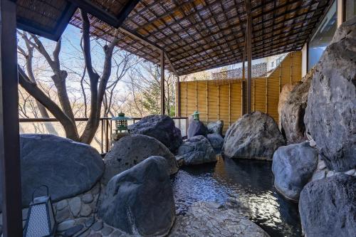 a pond with rocks in front of a building at Tabist Kinugawa Park Cottage in Nikko
