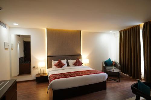 a hotel room with a large bed and a chair at The Terrace by Ladder Mgd by Citrine in Trivandrum