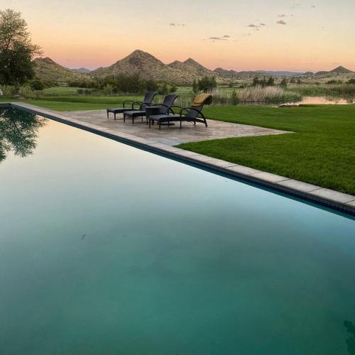 two benches sitting next to a pool of water at Big Sky Ranch in Colesberg