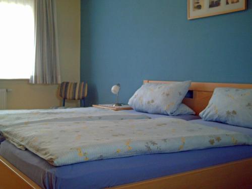 ein Schlafzimmer mit einem großen Bett mit blauer Wand in der Unterkunft Haus Nordseemelodie Wohnung 4  in Wittdün